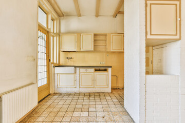 an empty kitchen with tile flooring and white cupboards on the wall, in a room that is being used for storage