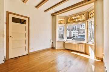 an empty living room with wood flooring and white brick walls in the background is a large window that looks out onto the street