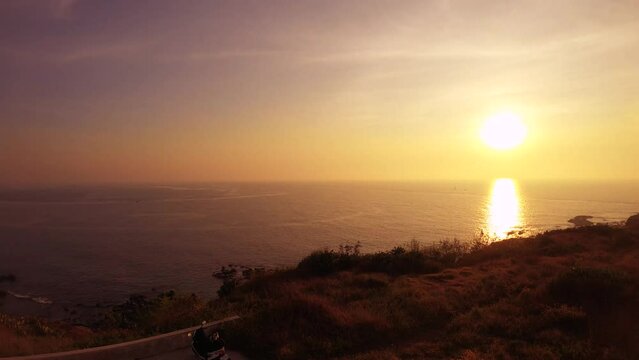 horizontal pane view of look out to ocean horizon with clam sea water during bright orange yellow golden sunset and reflection on the water at Hsi Dung Wei in Penghu Taiwan