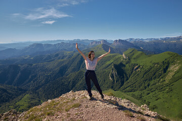 woman on top of mountain, raising arms. young woman with her arms up on top of a mountain