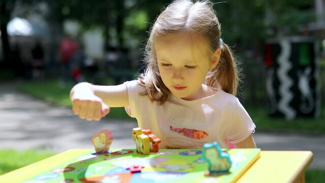 Adorable preschooler girl playing board game outdoors