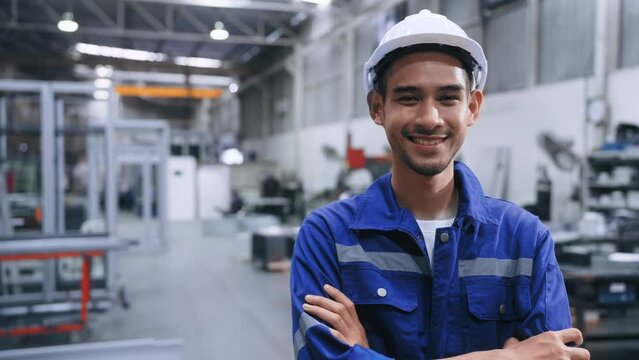 Professional worker Asian man standing and smile crossed arms having confidence among much of steel in warehouse at factory