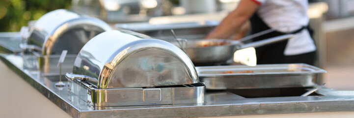 Row of chafing dishes closeup. Cooked meat vegetables and garnish are on large baking sheet. Food concept for restaurants and cafes