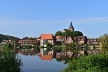 Fototapeta na wymiar Panorama mit Häusern und KIrche spiegelnd im See in Mölln 