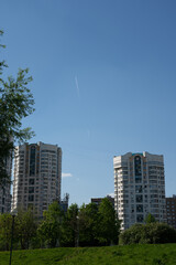 Two living buildings in the city with two planes in the sky.