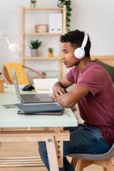 Man with wireless headphones working with laptop.