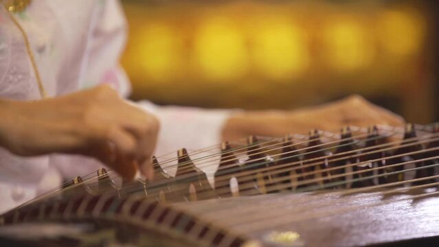 Asian woman fingering a harp to play music