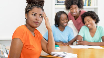 Black female student with problems at desk with group of learning african american students