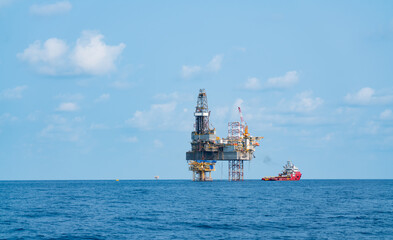 Offshore oil rigs in the Gulf and large supply ships nearby in sunny weather.