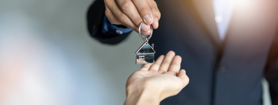 close up view hand of real estate agent realtor landlord giving key house to buyer
