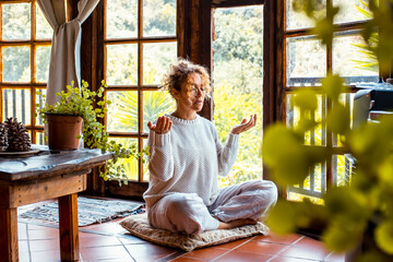 One woman at home indoor doing yoga asana meditation exercise for mental and body health. Healthy...