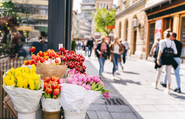 Sale of multi-colored flowers, bouquets of tulips on the street in a European city. Spring cityscape