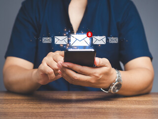 Businessman using a mobile receive a new message with email icons while sitting at the table.