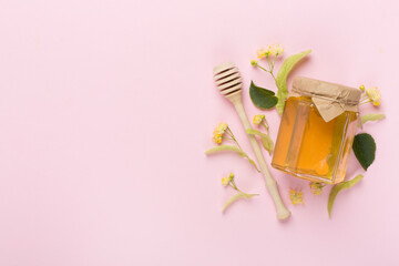 Linden honey with leaves and flowers on color backgroung, top view
