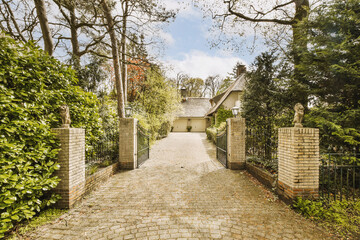 a gated driveway with trees and bushes in the foreground area behind it is an entrance to a house
