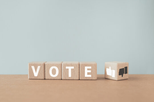 white VOTE text screen on wooden cube blocks with thumb up and down of flipped one. For makes a choice, votes for the correct decision, customer rating, review or feedback including copy space