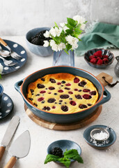 Traditional french pie clafoutis with fresh summer blackberry, blueberry and raspberry. Homemade sweet food. Selective focus.