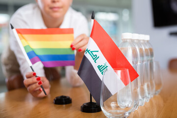 Preparing for business negotiations - woman sets small flags of countries of Iraq and LGBT on the...