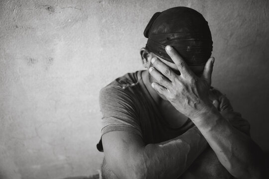 A drug addicted homeless man sitting alone and depressed in an abandoned house feeling anxious and lonely.