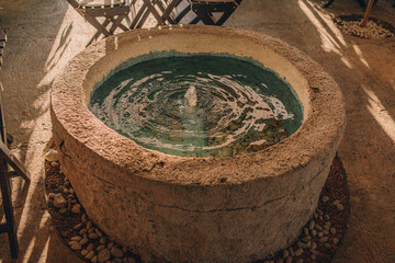 Balinese decorative garden stone basin with water. Tropical outdoor fountain decor, garden wash...