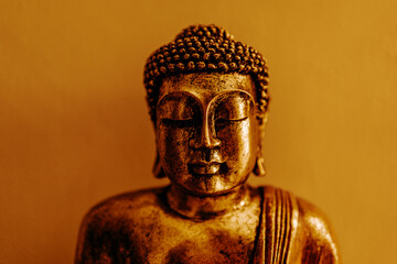 Golden buddha statue portrait in sitting meditation pose on wall background. Buddhism religion...