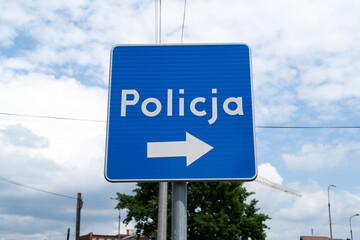 Police information road sign in Poland, indicating the location of a police station. Letters in Polish language, Policja means Police. © Longfin Media
