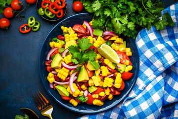 Spicy summer salad with sweet corn, red beans, avocado, jalapeno, red tomatoes, onion and fresh...