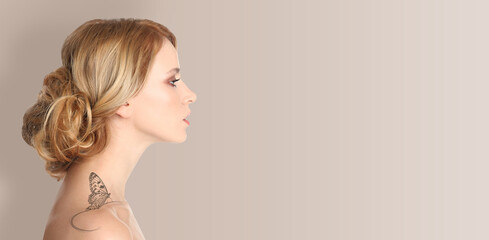 Young woman with beautiful butterfly tattoo on beige background, side view. Banner design with...