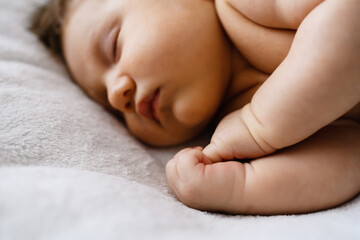 Sweet sleeping newborn baby fists in bed