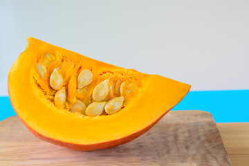 A quarter of an orange pumpkin with seeds on a blurred background