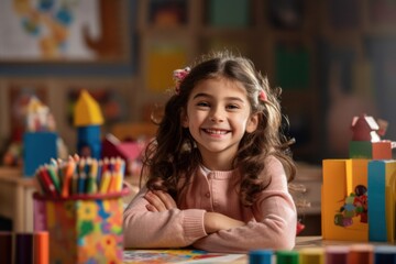 Smiling girl surrounded by colorful educational materials while participating in an art class. Back to school