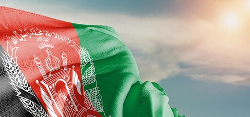 Afghanistan national flag cloth fabric waving on beautiful sky Background.