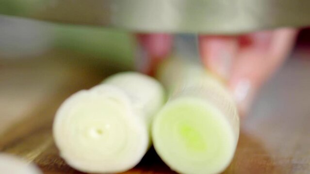 Detail shot, cutting spring onion on a chopping board.