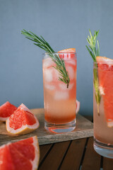 Paloma cocktails outdoors in natural light. Cocktails with tequila garnished with rosemary twig.