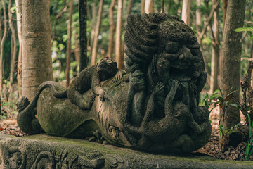 Old monkey sculpture in sacred monkey forest. Indonesian stone statue in monkey sanctuary