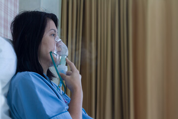 Sick beautiful female in blue cloth hold nasal mask with respiratory problem in hospital room....