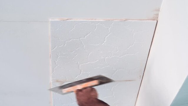 adhesive plaster application of styrofoam ceiling tiles of a home kitchen