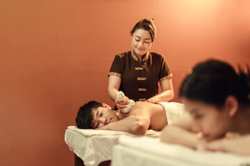 Selective focus, Asian mature female masseuse serve customers, doing Thai herbal compress back with...