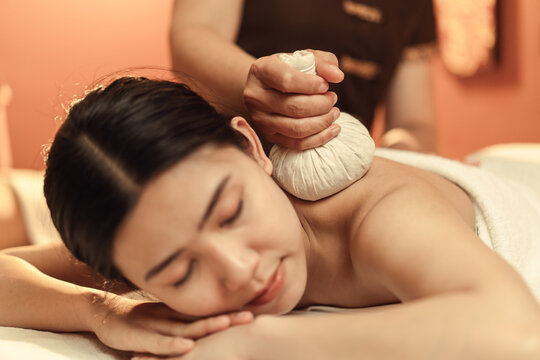 Selective focus, Herbal compress on hand of masseur. Relaxation Asian woman having Thai herbal compress massage in beauty spa centre. Body care.