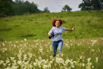 Naklejka na ściany i meble Woman photographer running on a meadow