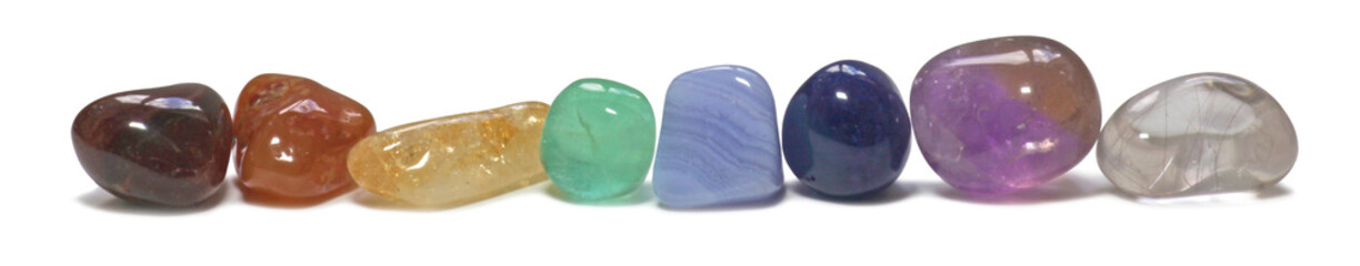 Neatly aligned single row of chakra colored tumbled healing crystal semi precious gem stones...