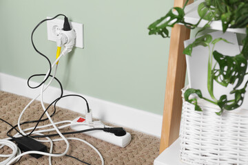 Different electrical plugs in socket and power strip on floor indoors