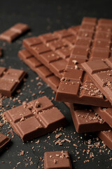 Pieces of tasty chocolate bars on grey table, closeup