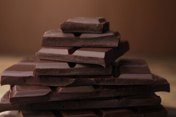 Pieces of tasty chocolate on blurred background, closeup