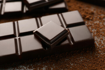 Delicious dark chocolate and cocoa powder on table, closeup