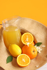 Glass jug and citrus fruits in a summer hat. Lemonade from oranges and lemons.