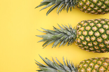 Delicious ripe pineapples on yellow background, flat lay. Space for text