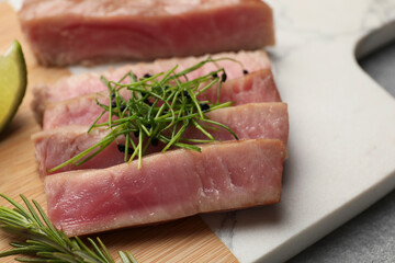 Pieces of delicious tuna steak with microgreens and rosemary on board, closeup