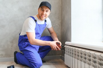 Obraz premium heating system installation and maintenance service. plumber installing radiator.