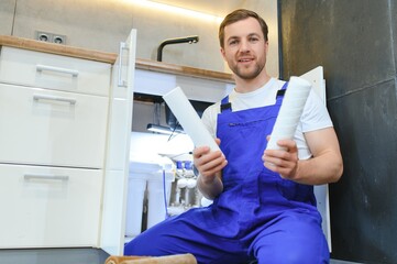 Plumber working change cartridge filter for water in kitchen. Concept filtration system.